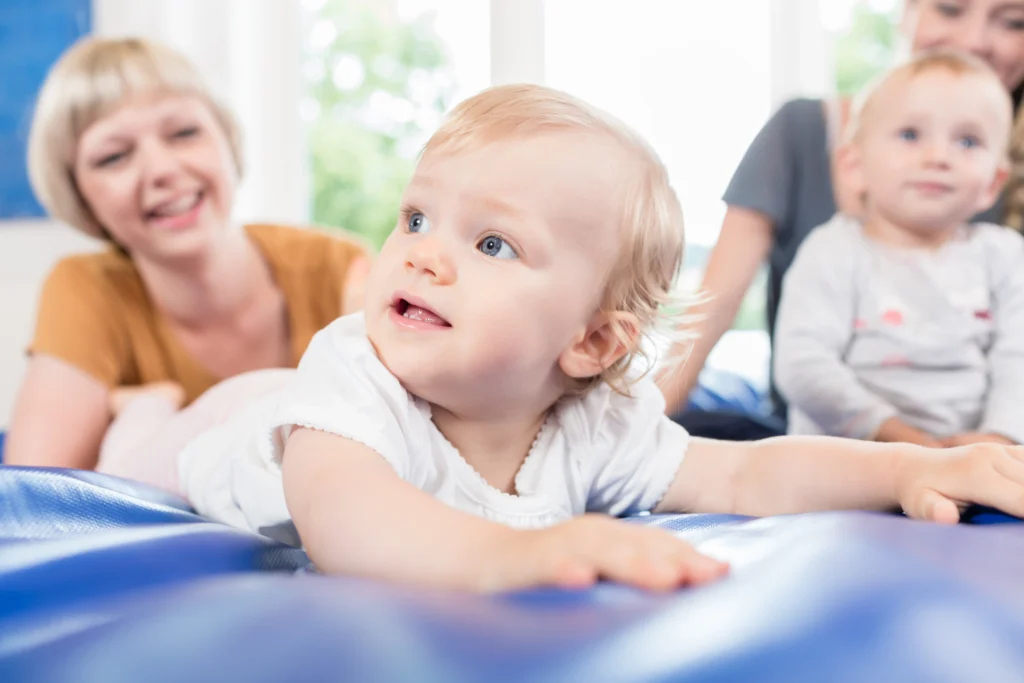 Kleinkinder und ihre Eltern bei einem fröhlichen Kurs im Familienzentrum Schärding, spielend auf einer blauen Matte.