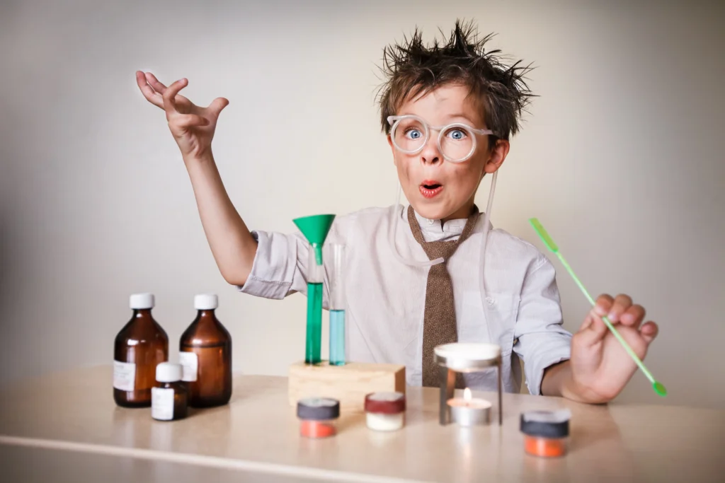 Ein Junge mit zerzausten Haaren und Brille spielt als kleiner Wissenschaftler bei einem Experiment mit Laborutensilien.