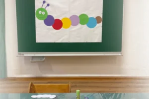 Eine bunte Raupe aus Papier an einer grünen Schultafel in einem Gruppenraum für Kinder im Familienzentrum Schärding/Andorf.