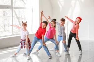 Eine Gruppe fröhlicher Kinder in einem hellen Raum beim gemeinsamen Tanzen oder bei einer spielerischen Bewegungsübung.