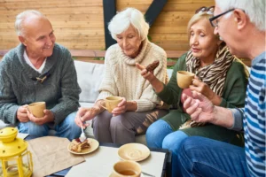 Eine Gruppe von Senioren sitzt gemütlich zusammen, trinkt Kaffee und genießt gemeinsam ein Stück Kuchen im Freien.