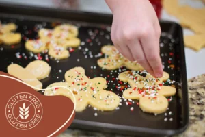 Ein Kind verziert glutenfreie Lebkuchenmänner auf einem Backblech mit bunten Streuseln für ein Familienbackevent.