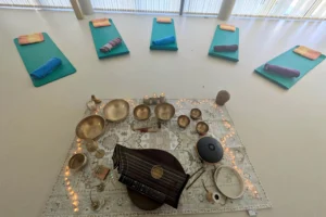 Ein Raum mit Yogamatten und Klangschalen, Zither sowie Kerzen auf einem Teppich für Entspannungsübungen im Familienzentrum.