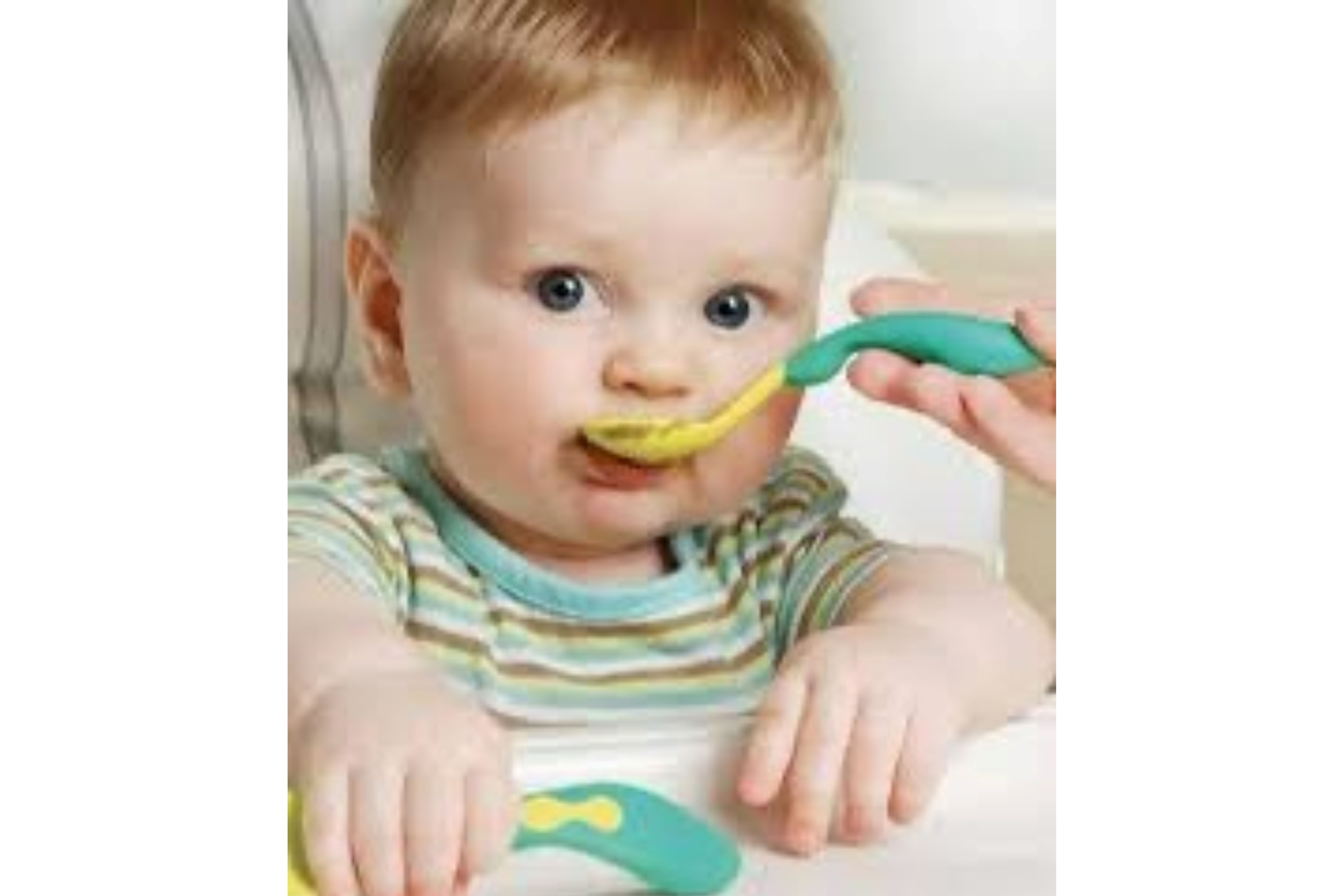 Ein Baby sitz in einem Hochstuhl, trägt eine gestreiftes T-shirt und hat einen Plastiklöffel in der rechten Hand. Gleichzeitig steckt eine fremde Hand dem Kind einen Löffel mit Brei in den Mund.